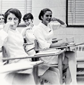 nurses seated at desks miming brushing teeth