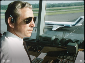 air traffic controller in tower with view of tarmac and plane