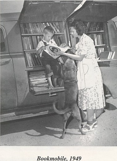 Family and their dog looking at books in the library's bookmobile.