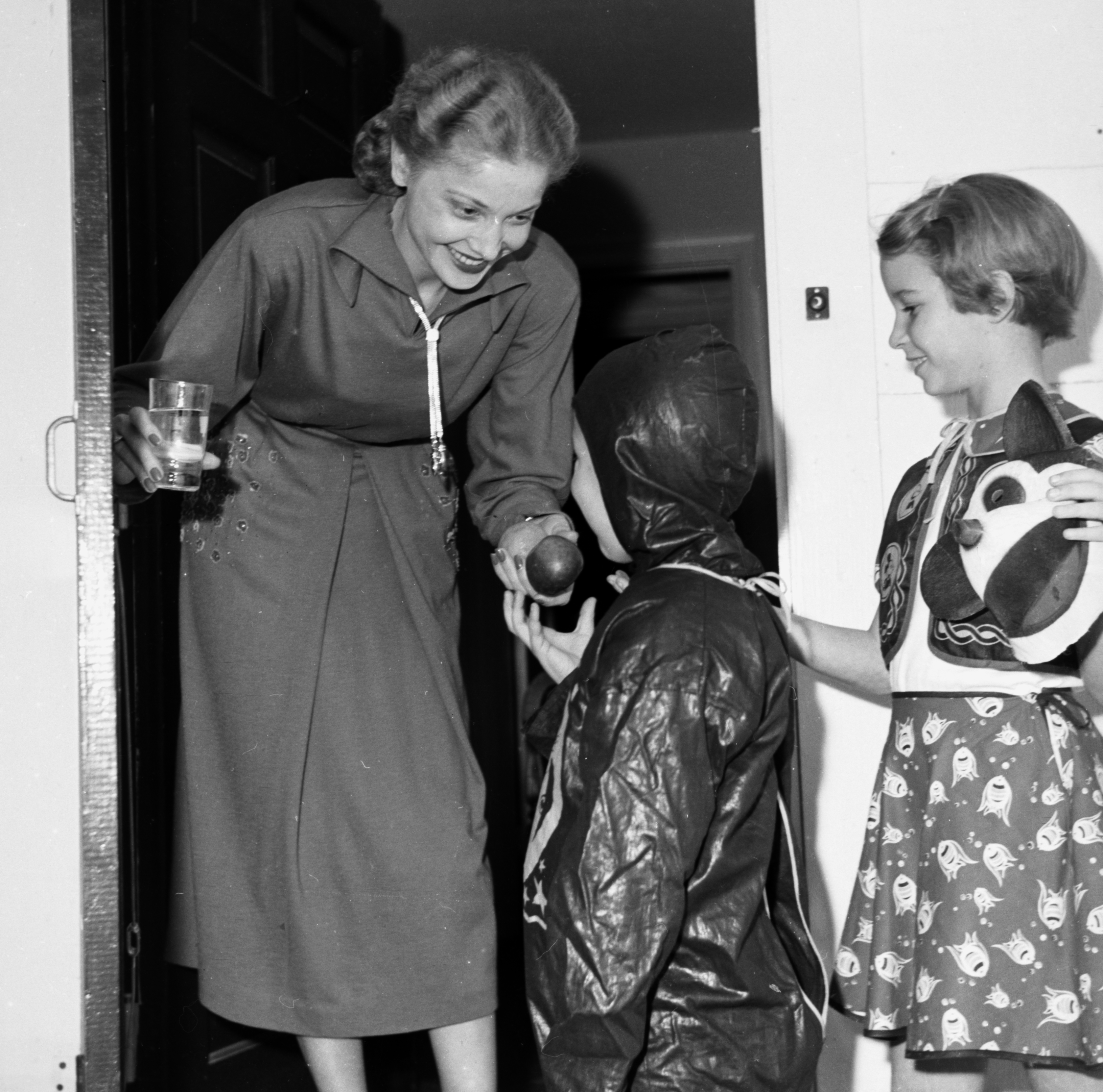 Image of two trick-or-treaters receiving an apple