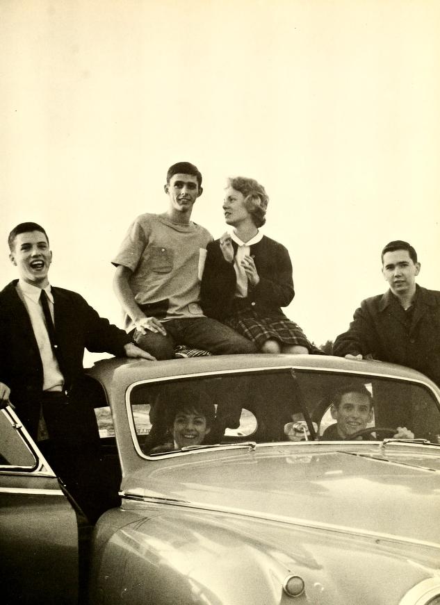 Image of students climbing out of and sitting on top of a car