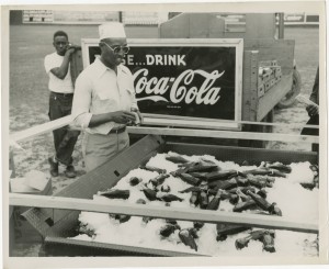 Man standing by an iced cart of Coca-Cola