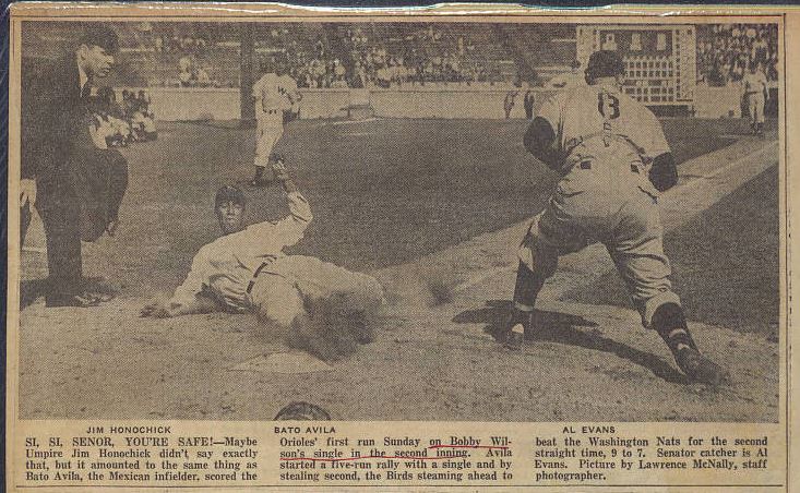 Baserunner sliding into home plate while the umpire looks on