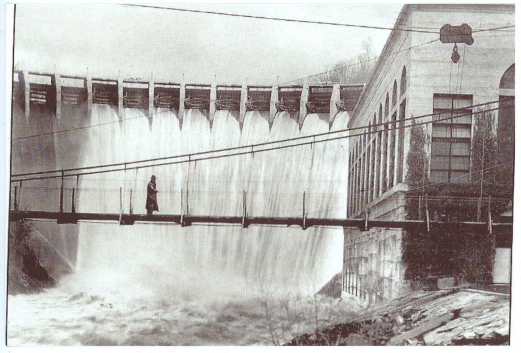 Man on a bridge in front of a dam