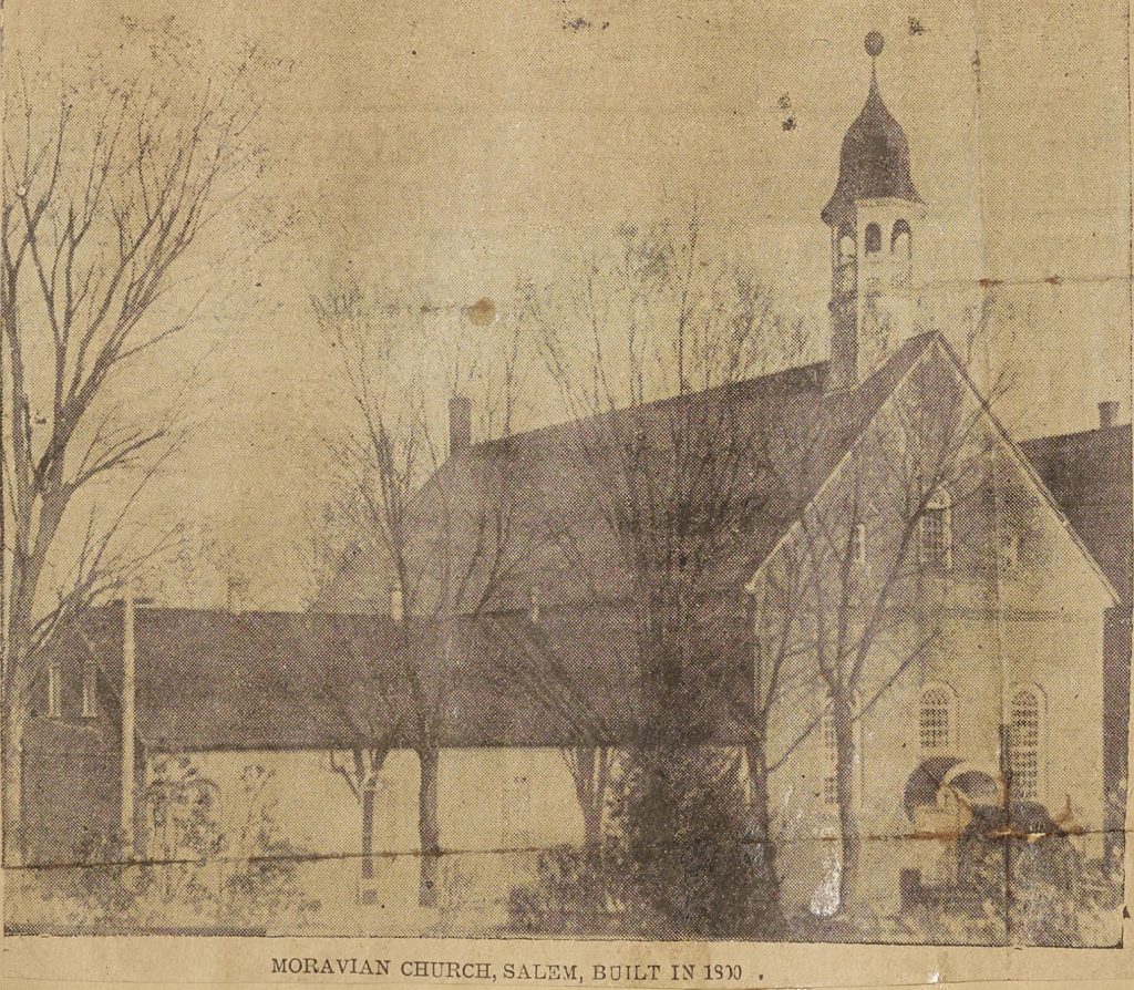 newspaper clipping of black and white photo of moravian church behind trees