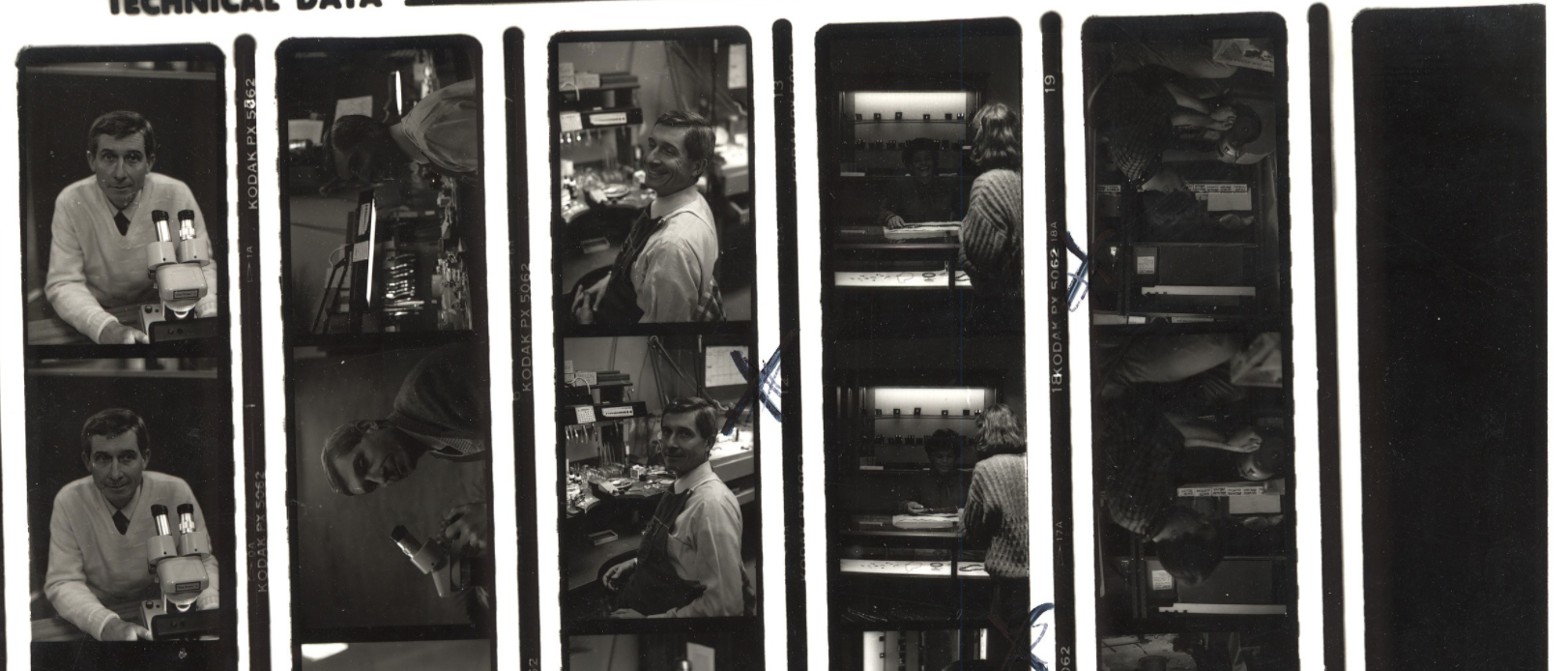 Close up crop of a black and white contact print of Baum Jewelry Craftsmen employees working in the store.