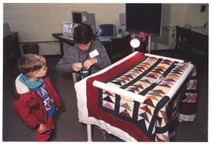 An older adult demonstrates a quilting technique during a Johnston Community College Open House.