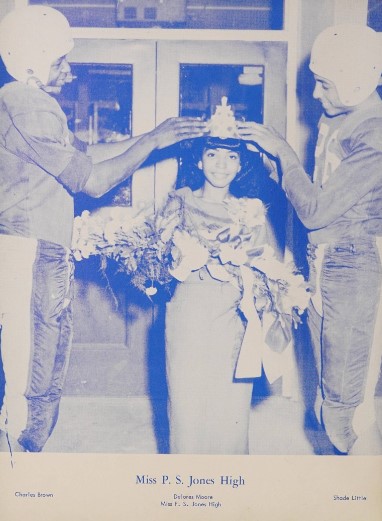 A photo from the yearbook depicting the crowning of Miss P.S. Jones by two football players.