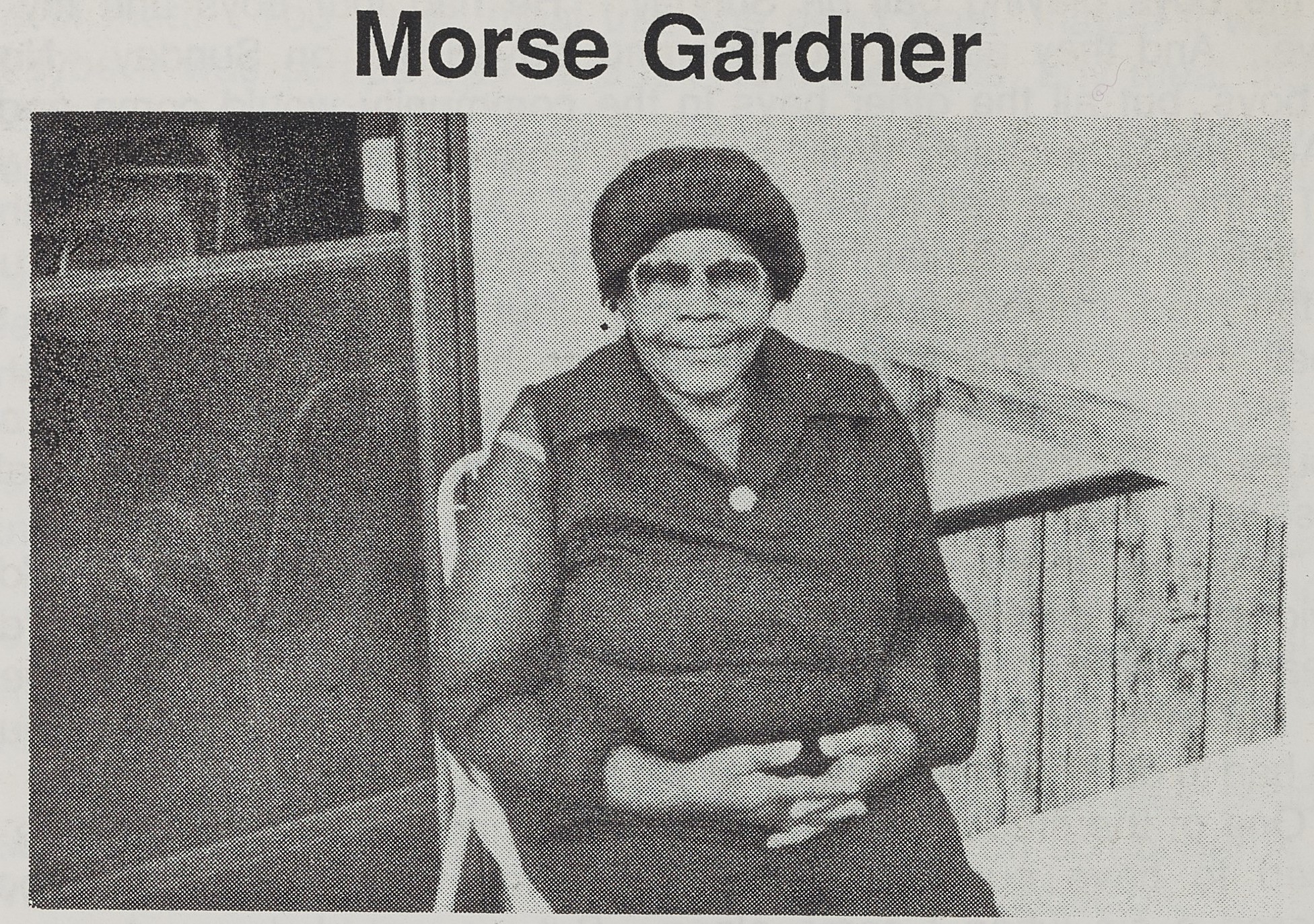 An older Black woman sits on the porch of her home.