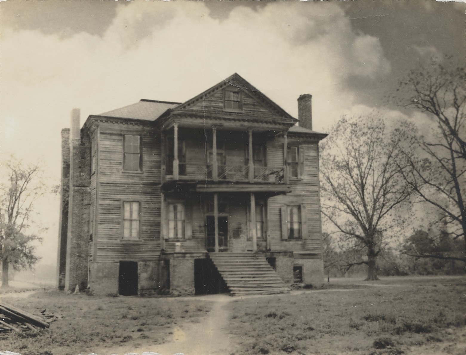 Black and white photograph of a run down mansion.