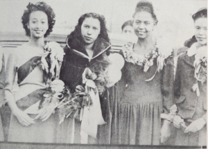 Four students standing side by side with flowers