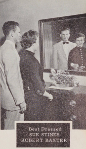 Photo of two teenagers standing beside each other and looking into a mirror. In the mirror, their faces are smiling.