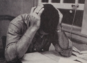 A student holding their head in their hands while studying, apparently stressed.