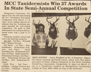 A newspaper clipping featuring a photo of a student standing in front of four taxidermy deer heads mounted on a wall.