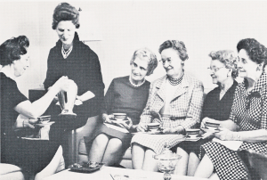A black-and-white photo of six people seated together, engaging in conversation