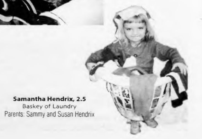 Child with a circular plastic laundry basket around them filled with clothes and a laundry detergent bottle.