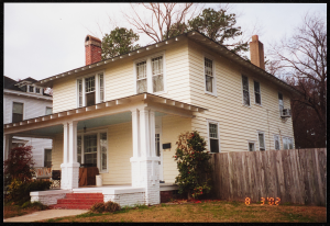 A view of the front and side of a yellow, two-story house