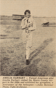 A photo of Amelia Earhart in a jumpsuit, in a field, walking toward the camera
