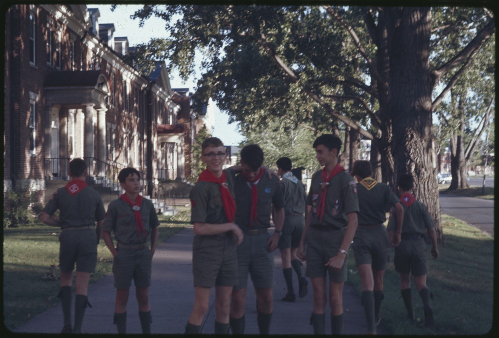 Group of individuals wearing uniforms standing around. In the center of the photo there is one individual that has their arm wrapped around another individual.