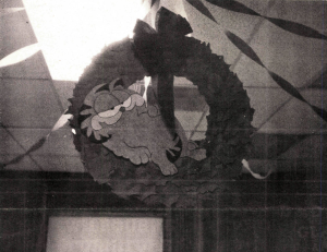 A black-and-white photo of Garfield the cat sitting in a Christmas wreath