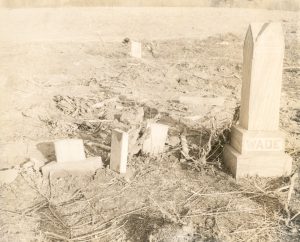 A black-and-white photo of graves askew after a storm. The tallest grave stone on the right says "Wade."