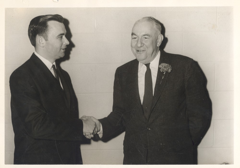 Two adults wearing suits shaking hands.  On the left is Bobby Franklin; on the right is former Senator Sam Erwin.