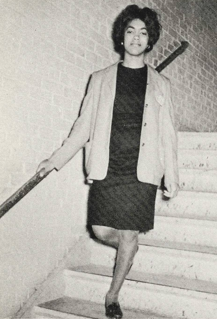 A student in a dress and blazer descending some stairs.