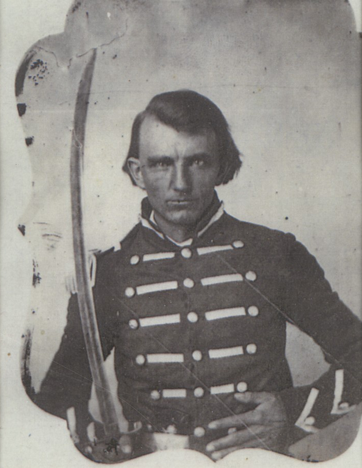 A black-and-white photograph of Wilson C. Daniels. He is wearing a Confederate Soldier uniform and holding a long sword.