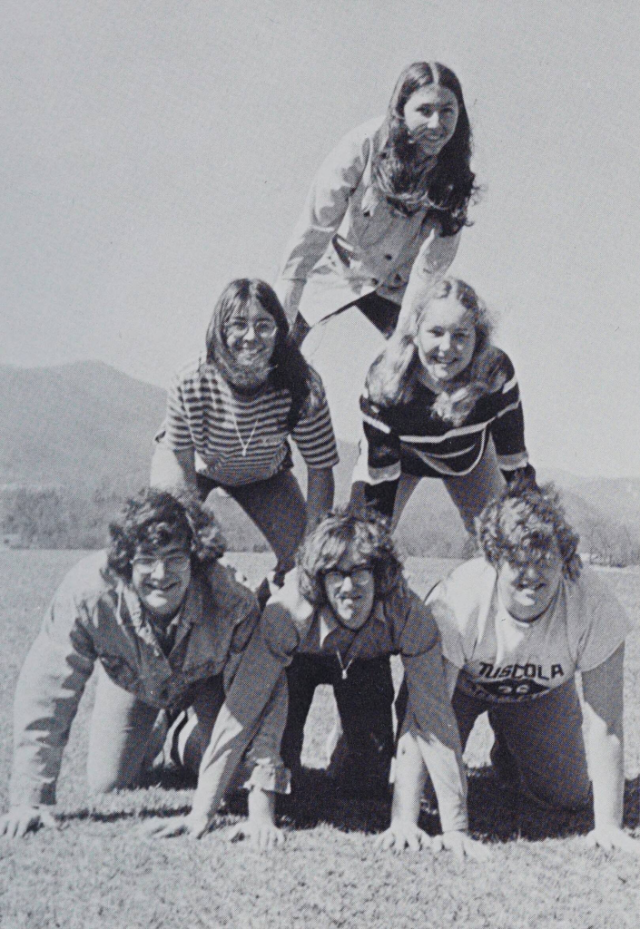 A black and white photo of six students on their hands and knees forming a human pyramid.