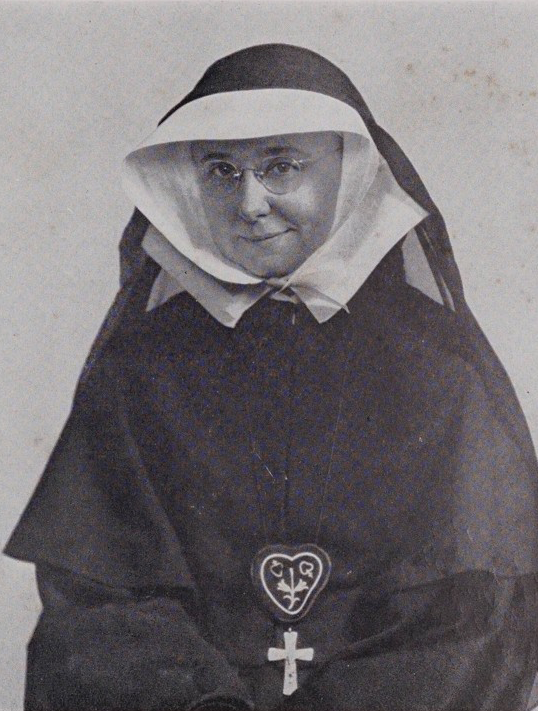 A black-and-white portrait of a nun with round glasses.