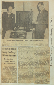 A newspaper clipping with a photograph of two adults standing on either side of a novel machine.