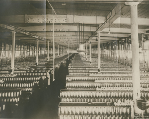 A photo of many rows of cotton spinning equipment within a mill.