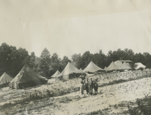 A photograph of a few people (possibly children) standing outside a group of tents.