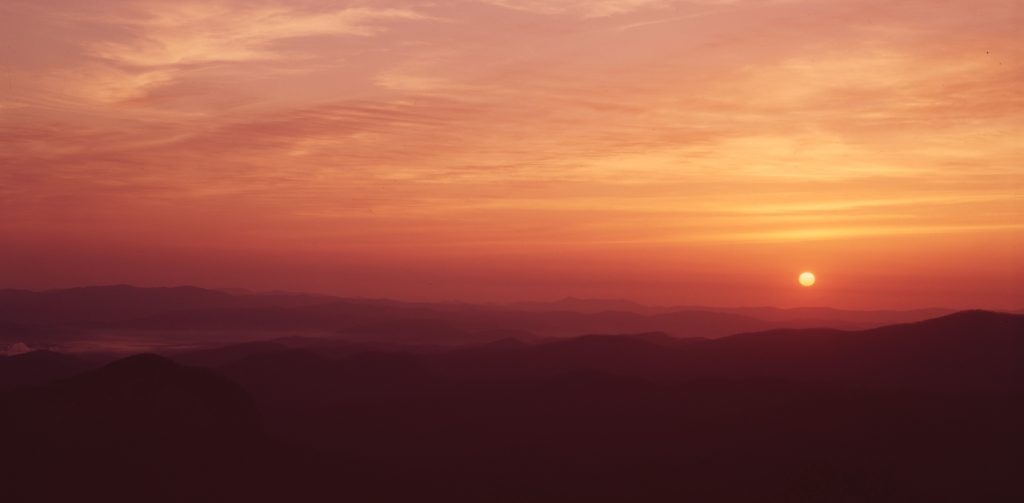 Mountains with the sun setting in the background.