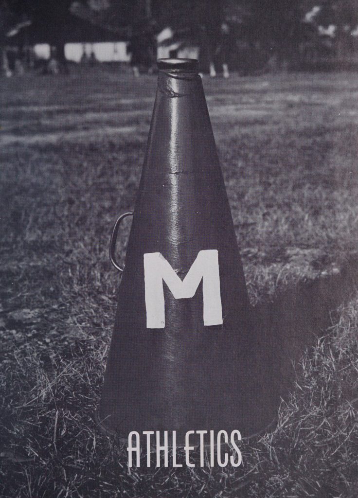 A cheerleading cone with the letter "M" painted on it sitting in a field