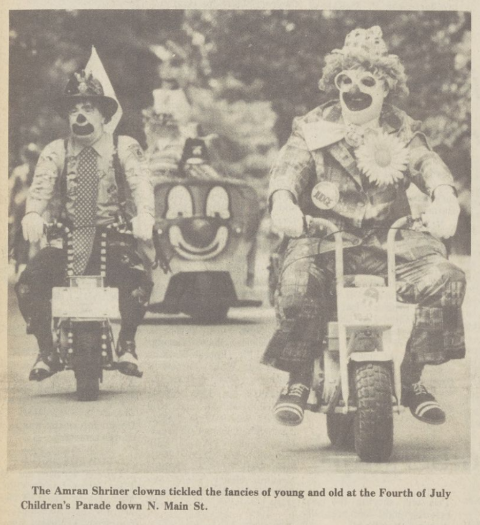 two clowns riding motorbikes in a parade