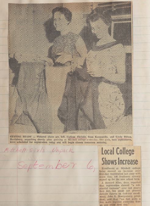 Newspaper clipping with a black and white image of two people standing next to each other while folding clothes in a college dorm room. 
