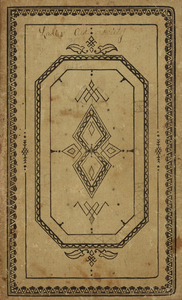 Tan color covered minute book with black ornamental designs. At the top of the cover is written in cursive: Ladies Aid Society.