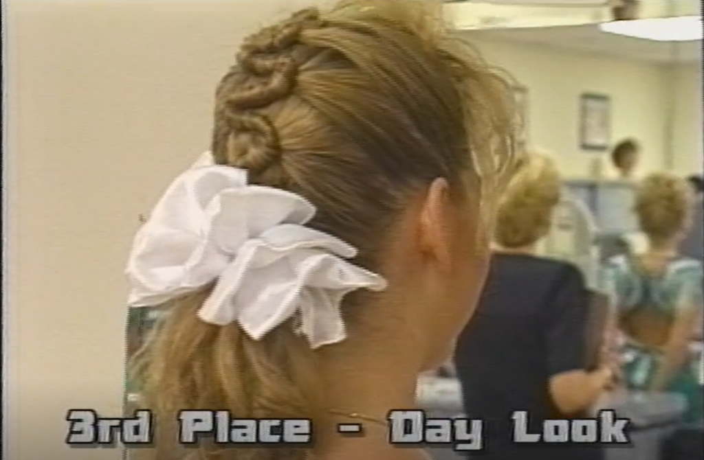 Back view of an individual styled hair. The styled hair features a white ruffle bow. At the bottom of the image is written: "3rd place - day look."