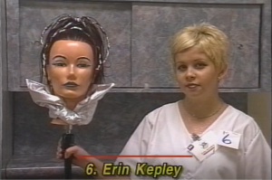 Individual posed with a mannequin with styled hair. At the bottom of the image is written: "6. Erin Kepley."