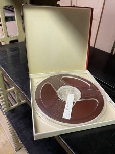 Open box holding a reel to reel tape