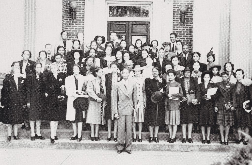 A large group of individuals standing on stairs in front of a building posed for a photograph.