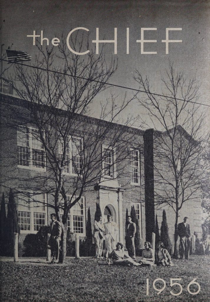 Facade of Etowah High School with students posed in front of it.  Image is black and white