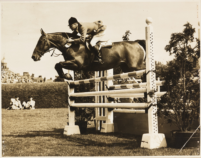 A photo of a gentleman on horseback clearing a jump.