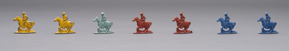 Metal game pieces painted in yellow, green, blue, and red depicting people in cowboy hats riding horses. 