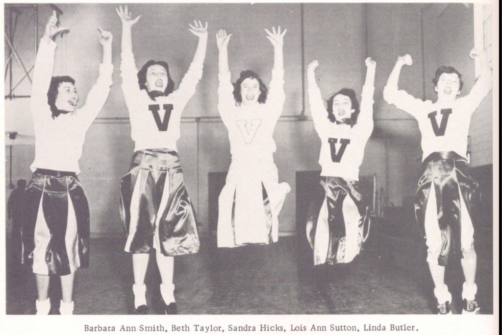 Five individuals dressed in 1950s cheerleading outfits jumping with their hands up. Their shirts have a V on the front. Caption under the image reads: Barbara Ann Smith, Beth Taylor, Sandra Hicks, Lois Ann Sutton, Linda Butler.