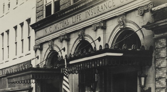 Building with two large awnings above double doors. Above the awnings, written in the stone, is "N. C. Mutual Life Insurance Co."