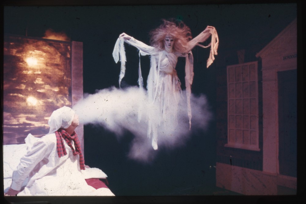 A color slide of a production of "A Christmas Carol," with the ghost of Christmas past hovering over Scrooge's bed.