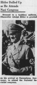 An article clipping from a newspaper on white paper with little damage. Includes a photograph of Adolf Hitler in Nazi uniform, with other uniformed Nazis surrounding him in the background.