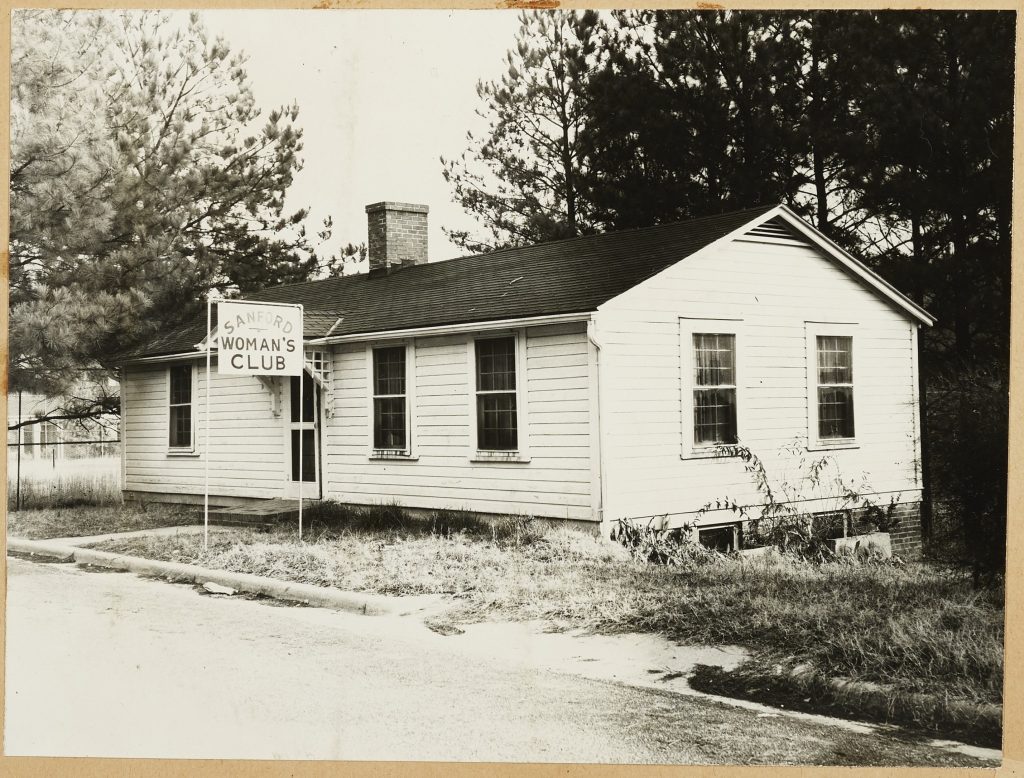 Image of a house with a sign posted our front that reads: Sanford Woman's Club.